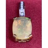 A 9 CARAT GOLD PENDANT WITH A TRANSLUCENT STONE AND CLEAR STONE CHIPS