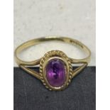 A 9 CARAT GOLD RING WITH A PURPLE STONE SIZE O/P