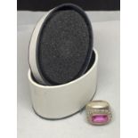 A BOXED SILVER RING MARKED 925 WITH A LARGE PINK RECTANGULR STONE ANS CLEAR STONE CHIPS