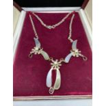 A DECORATIVE SILVER NECKLACE WITH RED AND PEARL COLOURED STONES IN A PRESENTATION BOX