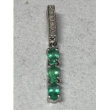 A 9 CARAT WHITE GOLD PENDANT WITH THREE IN LINE GREEN STONES AND CLEAR STONE CHIPS