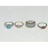 FOUR ASSORTED SILVER RINGS WITH CLEAR, BLUE AND ORANGE STONES
