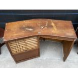 AN UNUSUAL MID CENTURY CURVED DESK WITH DROP DOWN ROLLER SHUTTER COMPARTMENT AND SHALLOW DRAWER -