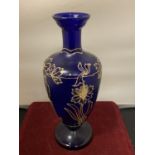 A BLUE GLASS URN WITH GOLD RELIEF FLOWER PATTERN (HEIGHT 26CM)