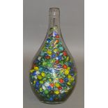 A large quantity of marbles contained in a glass bottle.