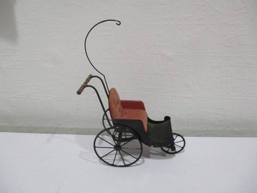 A metal dolls house carriage with leather button back seat