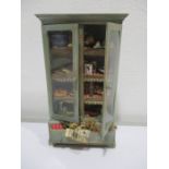 A wooden dolls house larder cupboard with a variety of miniature items on shelves