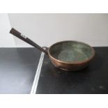 An antique copper handled saucepan