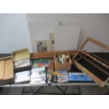 A collection of various artist materials including an easel, pastels, oils, brushes, canvas panels
