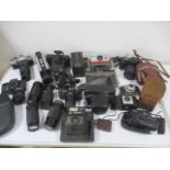 A collection of various cameras and lenses including Canon, Pentax, Kodak, Rollei film camera,