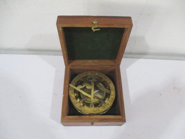 A brass sun dial and compass in wooden box