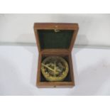 A brass sun dial and compass in wooden box