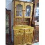 A pine dresser with glazed doors and cupboard under