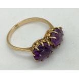 An unmarked gold ring set with a pair of oval amethysts