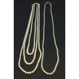 A triple string of faux pearls with a silver clasp along with one other