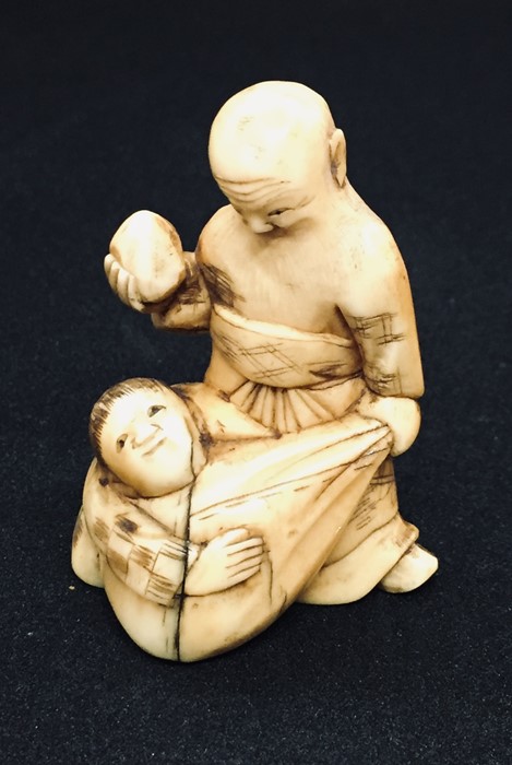 A 19th century carved Netsuke style figure of a bearded old man carrying a sack with a boy