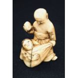 A 19th century carved Netsuke style figure of a bearded old man carrying a sack with a boy