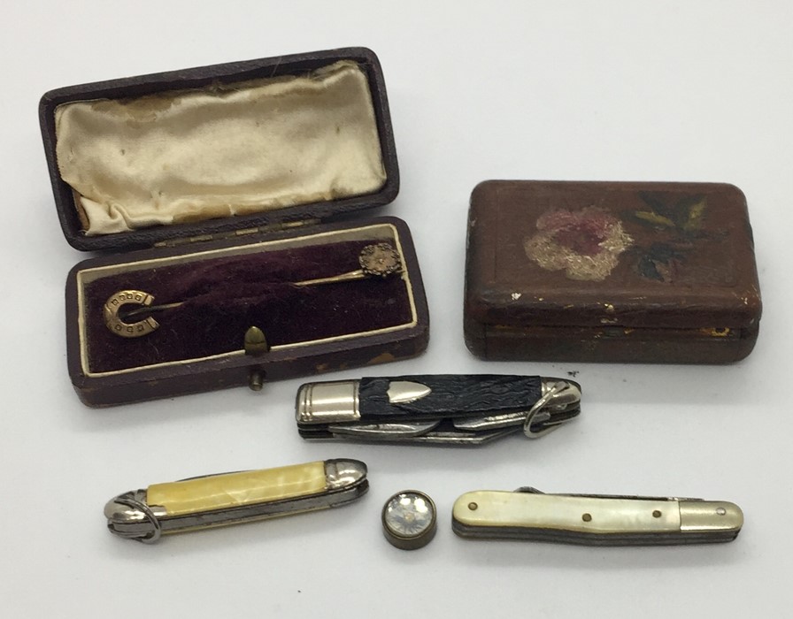 An airmans miniature compass along with three small penknives and two tie pins