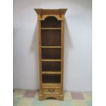 A tall narrow pine set of shelves with drawer under