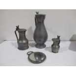 A large pewter lidded jug along with two others and a pewter hand mirror