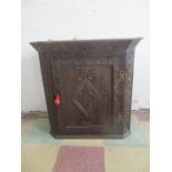 A carved oak hanging corner cupboard