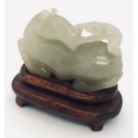 A pale green jade horse and monkey, carved with the monkey holding onto the horses turned head. With