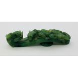 A green jade Chinese belt hook decorated with a dragon head and winged dragon. 8.2cm.