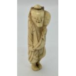 A 19th century carved ivory netsuke of a man carrying a gourd.