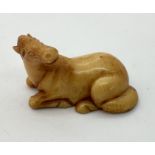 A signed netsuke of a recumbent horse with its head turned towards it's back.