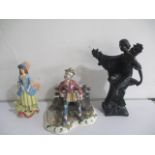A Capodimonte figure of a man on bench along with a bronzed figure of a lady and one other