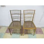 A pair of gilt faux bamboo regency style chairs with cane seats