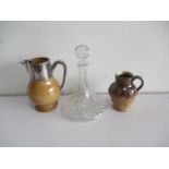 Two Doulton jugs, one with silver top, along with a glass ships decanter.