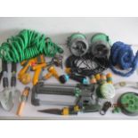 A collection of garden equipment including hoses, spray heads, tools, etc