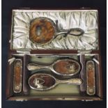 An Edwardian cased silver dressing table set decorated with tortoiseshell and silver inlay.