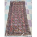 A red ground rug with geometric design, approx 190 cm x 90 cm