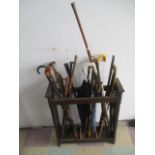 An oak stick stand, with a collection of walking sticks, umbrella's etc some with silver mounts.