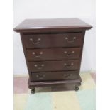 A small dark wood chest of four drawers on cabriole legs