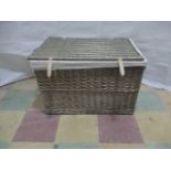 A wicker laundry basket with rope handles.