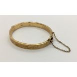 A 9ct gold hinged bracelet with safety chain. Weight 12g