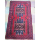 A handwoven red ground rug with geometric design