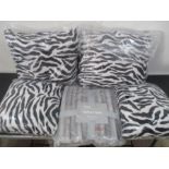 Four sealed Riva Home zebra cushions, along with a faux fur throw