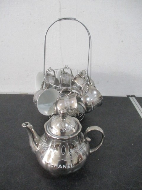 A Chanel porcelain tea set with silver colour glaze all decorated with the Chanel logo on stand- tea