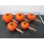 A set of five Le Creuset orange saucepans