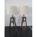 A pair of lamps on wooden tripods stands