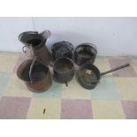 A collection of four cast iron pots and pans, along with two copper coal scuttles