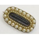 An unmarked gold mourning brooch set with seed pearls around a central lock of woven hair,