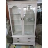 A painted display cabinet with three drawers under