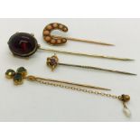 Two 9ct gold stick pins along with two others- the coral horseshoe interspersed with diamonds