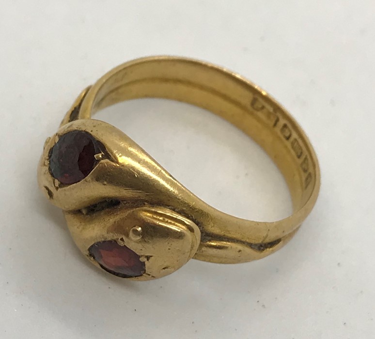 An 18ct gold double head snake ring set with garnets. Total weight 7g