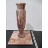 A pink marble vase along with a square stand